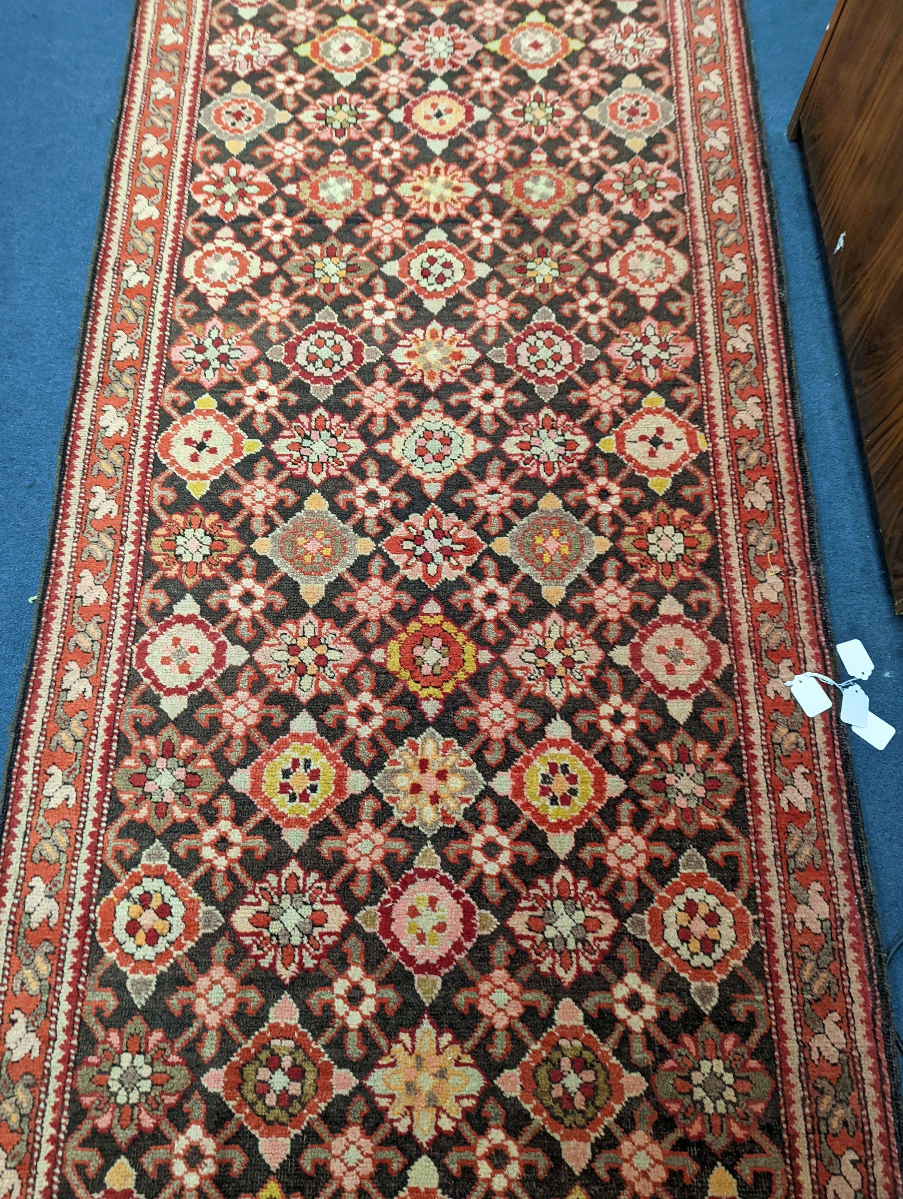 A North West Persian runner woven with rows of floral motifs, 575 x 110cm